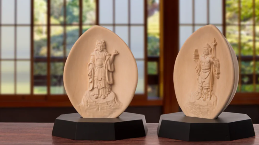 Two small peach-shaped Buddhist relief statues displayed on black bases.