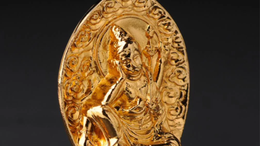 A golden Buddhist relief statue with an ornate halo and detailed carving, set against a dark background.