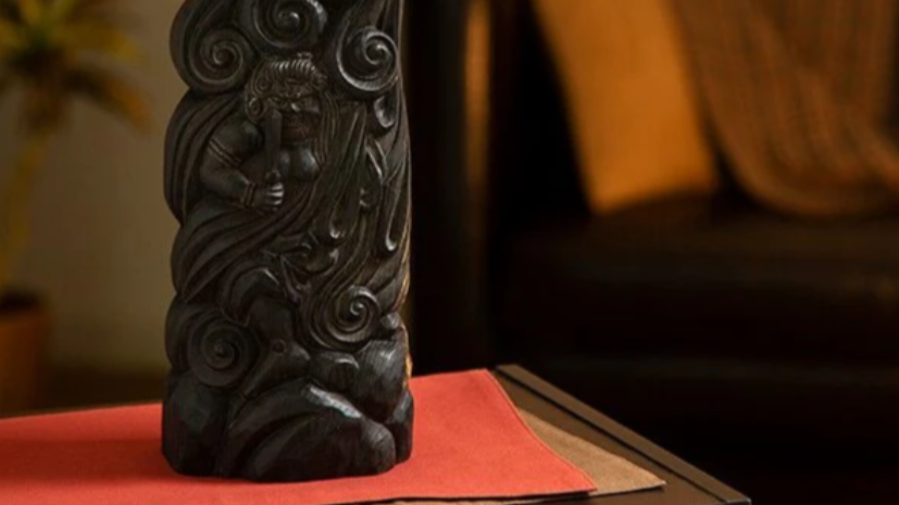 A dark Buddhist relief statue surrounded by cloud patterns, placed on a red cloth.
