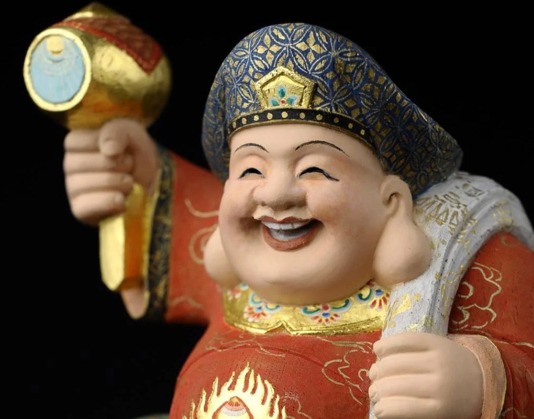 Smiling Daikokuten statue holding a lucky mallet and treasure sack, representing the Japanese fortune deity’s connection to Mahakala in Buddhist tradition.