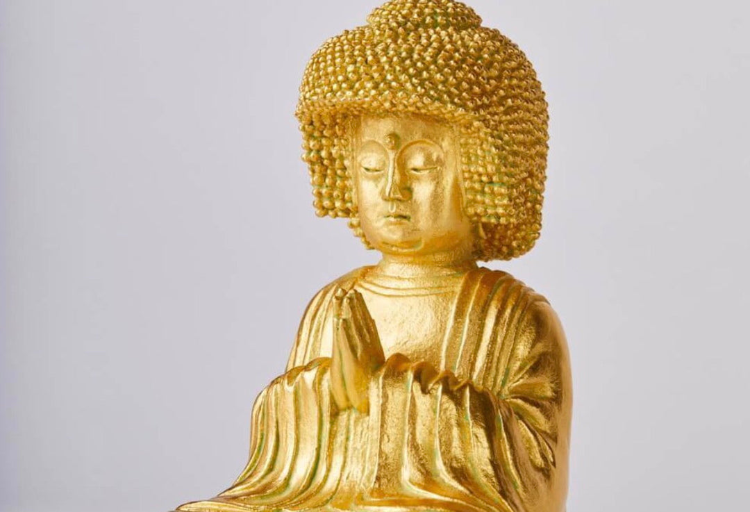 Golden Buddha statue with tightly curled hair and hands held before the chest, illustrating visual features used to compare Amitabha Buddha with the Historical Buddha.
