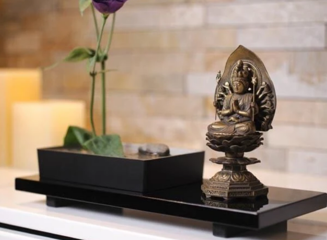 Multi-armed Guanyin statue seated on a lotus pedestal in a calm home setting, illustrating Avalokiteshvara iconography in Buddhist art.