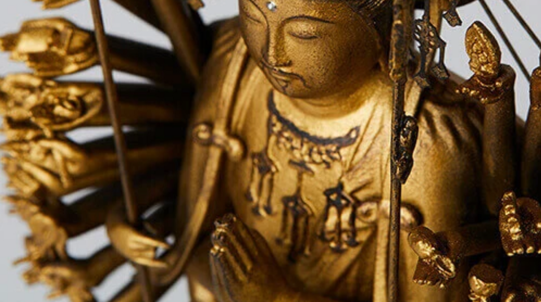 Senju Kannon statue seated on a lotus pedestal with multiple arms and ritual objects, illustrating the symbolic meanings of 1000-armed iconography in Buddhist art.
