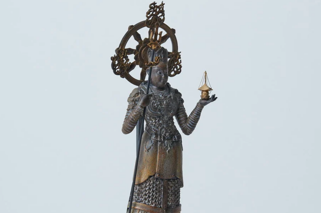 Armored Buddhist guardian statue holding a staff and sacred pagoda, illustrating the weapons and ritual objects associated with the Four Heavenly Kings.