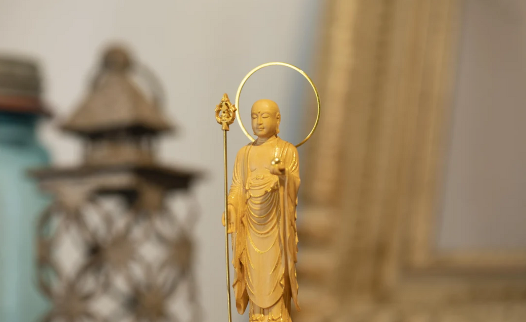 Standing Jizo statue holding a staff and wish-fulfilling jewel, illustrating the symbolic attributes commonly seen in Jizo statues.