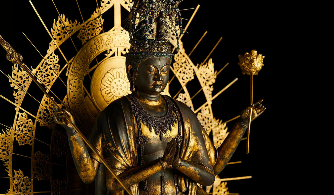 Ornate Guanyin statue with multiple arms and a radiant golden halo, representing prayer, compassion, and devotional practice in Buddhism.