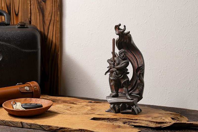 Wooden Fudo Myoo (Acala) statue standing with sword and flaming halo, displayed on a wooden table