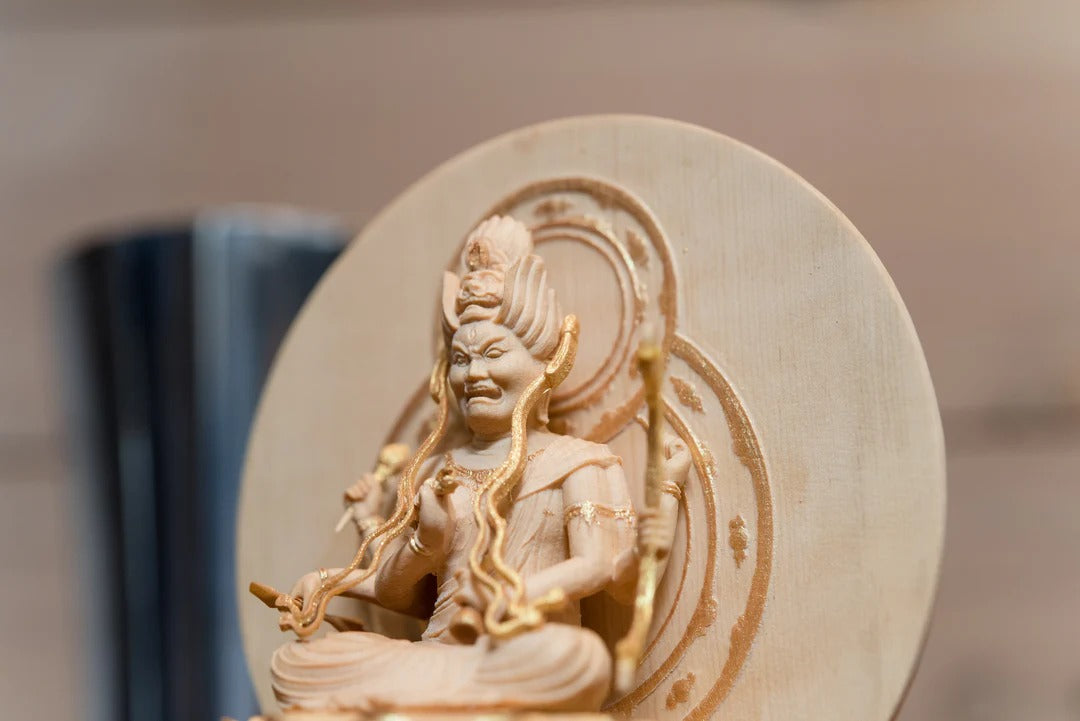 Wooden Fudo Myoo (Acala) statue with a halo, seated and holding a sword and rope, shown in close-up